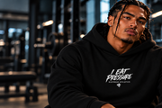 Seated man wearing the black I EAT PRESSURE microterry pullover hoodie